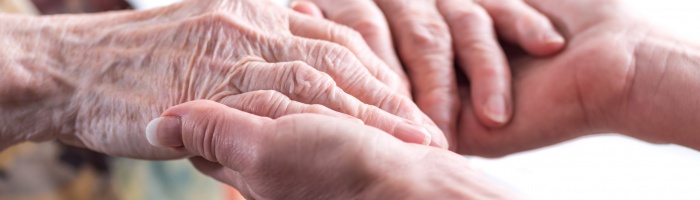 Hands of young woman holding the hands of an elderly person